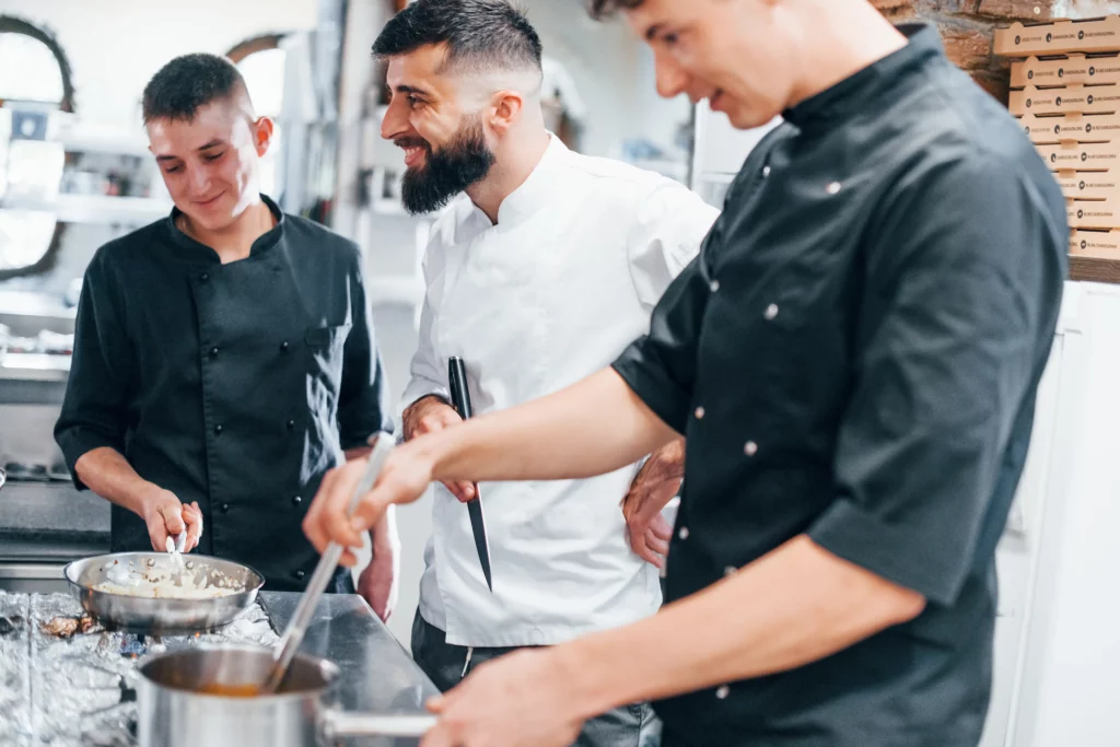 Chef Luca Ferraro in the kitchen with his team, smiling and preparing fresh, wholesome recipes for Cooks in a Flash.